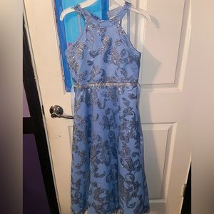 Patterned glitter dress with an open back. Jewel accents and blue ribbon ties.